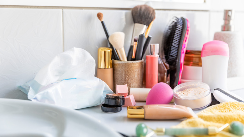 cluttered bathroom counter with makeup and daily hygiene products everywhere